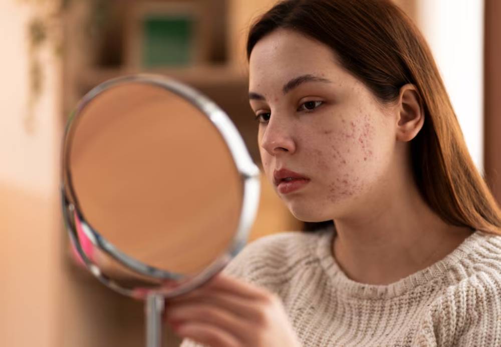 A woman in a cozy sweater gazes into a handheld mirror, softly lit by warm indoor lighting, surrounded by a peaceful setting.