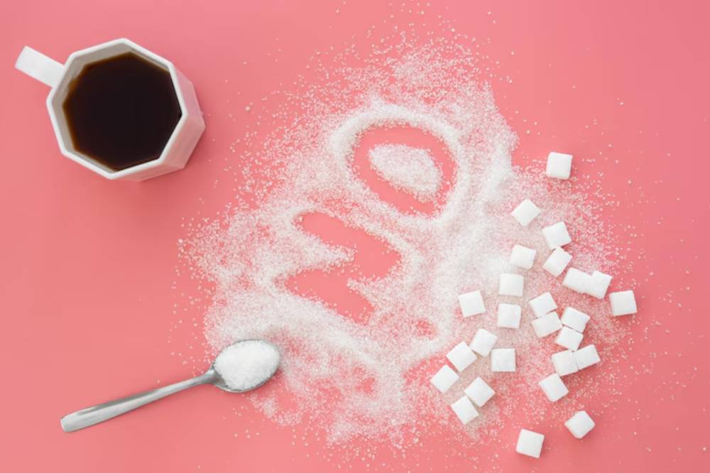 A pink background features coffee, granulated sugar, and sugar cubes, with 