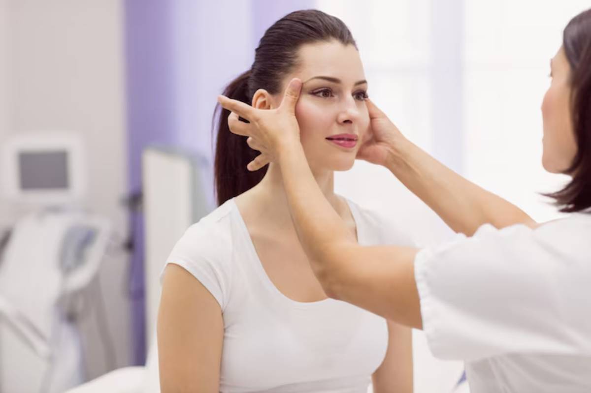 A dermatologist examines a patient's skin in a bright medical office, focusing on assessing or treating a condition.